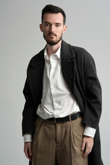 Stylish young man in a classic outfit posing in a studio