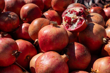 Fresh pomegranates displayed at a vibrant market in autumn sunlight