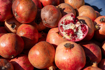 Fresh pomegranates displayed at a vibrant market in autumn sunlight