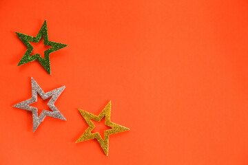 Season's greetings scene. Origami stars, sparkling stars on a orange background. Flat lay. orange backdrop text or ad space
