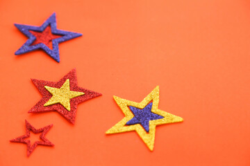 Season's greetings scene. Origami stars, sparkling stars on a orange background. Flat lay. orange backdrop text or ad space
