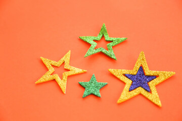 Season's greetings scene. Origami stars, sparkling stars on a orange background. Flat lay. orange backdrop text or ad space
