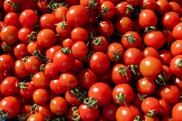 Fresh red cherry tomatoes piled at a local market during sunny midday hours