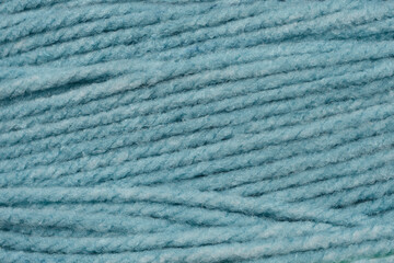 A close-up texture shot of light blue yarn, showing its soft, intertwined strands