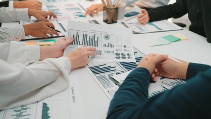 A group of professionals collaborates on data analysis, sharing insights through various charts and graphs laid out on the meeting table in a modern office. SACTR