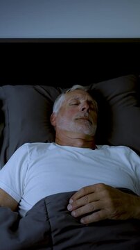 Mature adult sleeping at night. Vertical Video.
