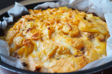 Moussaka is a Balkan oven dish. Potatoes, minced pork, fried onions in layers. Yogurt or sour cream mixed with eggs baked on top. Baking sheet with moussaka on baking paper. Serbian version of cooking