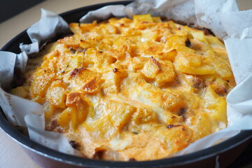 Moussaka is a Balkan oven dish. Potatoes, minced pork, fried onions in layers. Yogurt or sour cream mixed with eggs baked on top. Baking sheet with moussaka on baking paper. Serbian version of cooking