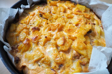 Moussaka is a Balkan oven dish. Potatoes, minced pork, fried onions in layers. Yogurt or sour cream mixed with eggs baked on top. Baking sheet with moussaka on baking paper. Serbian version of cooking