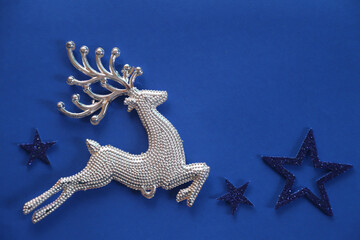 Beautiful Christmas silver deer close up isolated on a blue background. Adorable reindeer with presents for christmas decoration.
