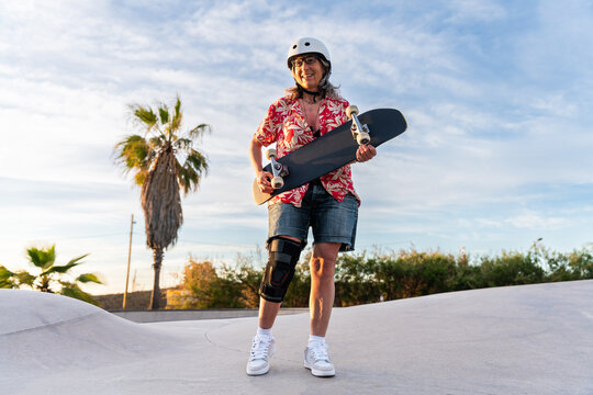 Beautiful active senior woman skateboarding at skate city park - Mature adult female skateboarder having fun, concepts about elderly, modern lifestyle and green mobility - Powered by Adobe