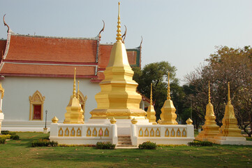 Golden chedis (stupas) at Wat Thawonwararam temple in Kanchanaburi, Thailand, surrounded by lush...
