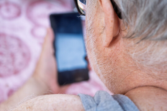 Elderly man browsing internet on smartphone relaxing on bed