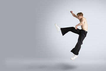 topless man jumps high in a white isolated studio, flying backwards with ample copy space, showcasing dynamic motion and energy