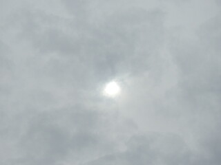 A bright sun peeking through a cloudy sky. Natural texture, background.