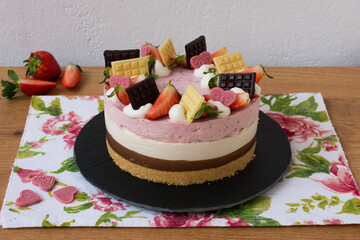 Strawberry, vanilla and chocolate cake decorated with chocolates and strawberries. Neapolitan cake