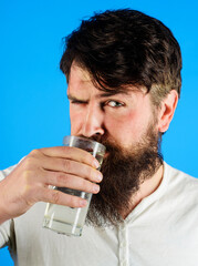 Closeup portrait of bearded man drinking glass of water at morning. Healthy nutrition. Man drinking...