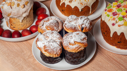 An assortment of beautifully decorated Easter cakes and red eggs are arranged on a wooden table.