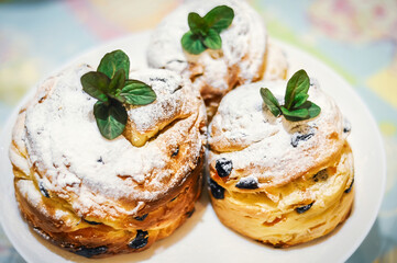 Three craffins sprinkled with powdered sugar and garnished with fresh mint leaves on a white plate.