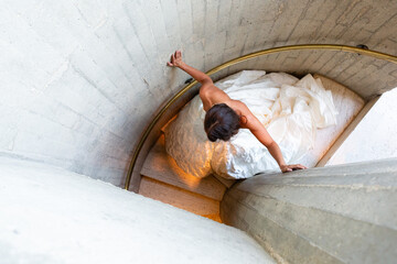 Bride in a flowing gown descending a spiral concrete staircase