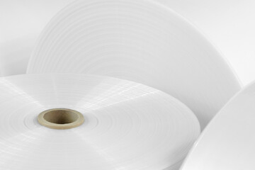 Rolls of white polyethylene film for the production of packages and packaging are shown close-up....