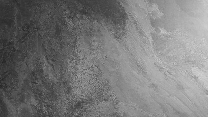 A grey wall with a few cracks and a few spots. The wall is made of stone and has a rough texture