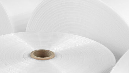 Rolls of white polyethylene film for the production of packages and packaging are shown close-up. The roll is white and has a brown center