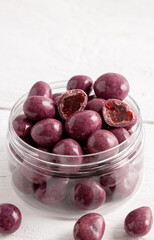 Dried fruits in chocolate glaze. Candies in a glass jar. Close-up.