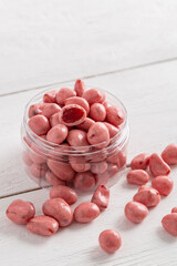 Dried fruits and berries in chocolate glaze. Pink candies on a white wooden background.