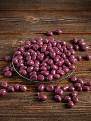Burgundy chocolates on a brown wooden background. Sweets in a glass plate.