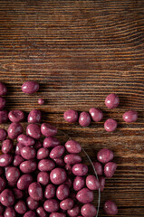Burgundy chocolates on a brown wooden background. Sweets in a glass plate.