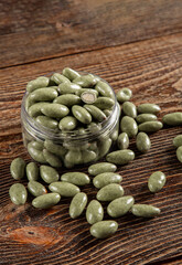 Green chocolates on a brown wooden background. Sweets in a glass jar.