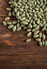 Green chocolates on a brown wooden background. Sweets in a glass plate. Filling is a nut.