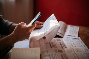 A man pays utility bills online using a QR code in an app using a smartphone in the kitchen....