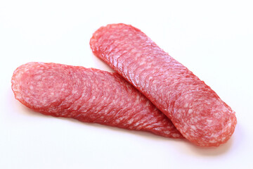 Thinly sliced ​​salami sausage close-up. Side view of tasty sliced ​​sausage. Appetizer. Sausage on white background