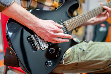 Man playing black electric guitar in recording studio