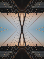Fototapeta premium Intricate mirrored geometric lines and shapes converge in a symmetrical pattern, capturing a hi-tech abstract aesthetic against a vibrant sunset skyline.