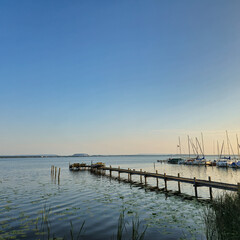A Serene and Beautiful Waterfront View featuring a Pier, Sailboats gently floating at Sunset...