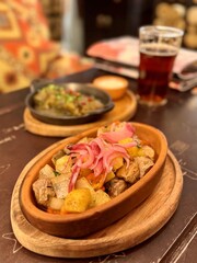 This dish features flavorful pork, paired with roasted vegetables and mango pickled onions for an exquisite meal next to glass beer. Close-up