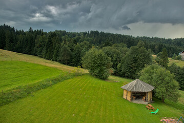 Altanka w ogrodzie w górach, na horyzoncie las, burzowe chmury © Stefan