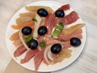 A bright dish with assorted dried meat, sliced olives and fresh herbs, ideal for any feast. Close-up