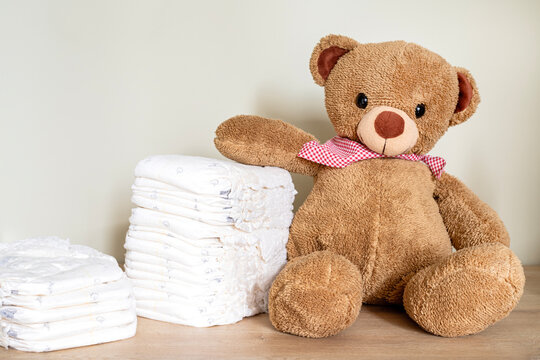 Stack of diapers with toy teddy bear on table.Newborn nappies concept
