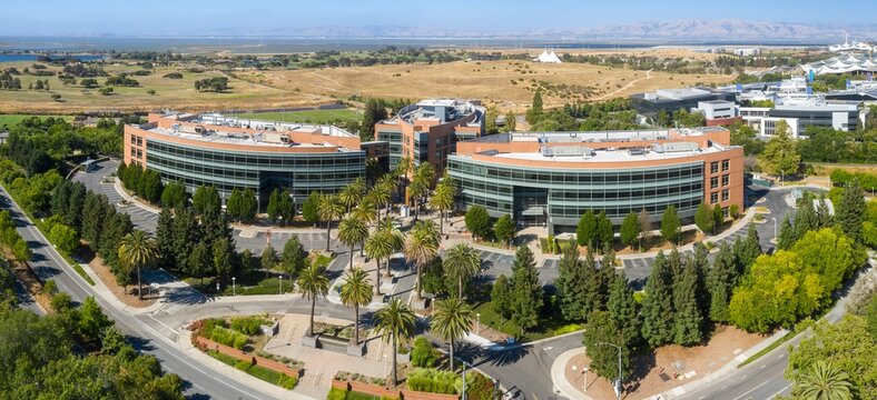 Aerial view of Googleplex office buildings, lush landscaping, and city streets. Sunny day, business district. Mountain View, California, USA. 18 June 2024