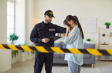 Portrait of a young woman crime victim covering face with hands standing with policeman putting his...