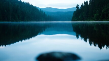 Tranquil lake view reflecting misty mountains and dense forests during the early morning hours : Generative AI