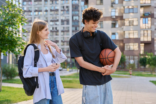 Young laughing teenage guy and girl talking together, urban background