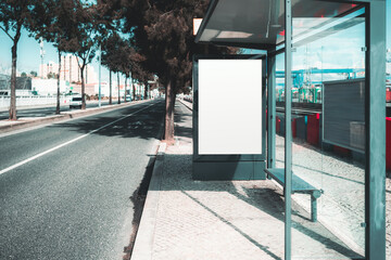 Blank advertising billboard mockup at a modern bus stop with glass walls. Urban street with bicycle...