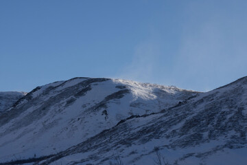 Light on top of mountain with wind blowing snow