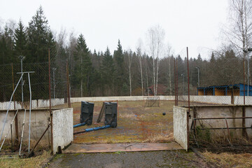 An abandoned multi-purpose sports field for basketball, hockey, and football. Hockey boards, small goals, and a ball