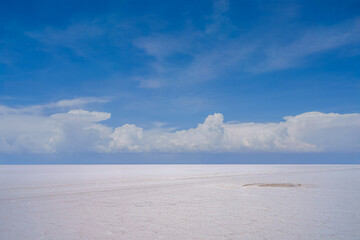 Symmetrical cloudy sky reflection in the water surface of Salar de Uyuni in Bolivia with soft focus